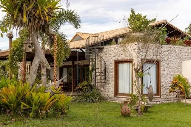 Casa de piedra con escalera de caracol y jardín tropical