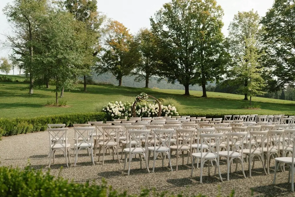 Sillas blancas acomodadas en un jardín para la ceremonia